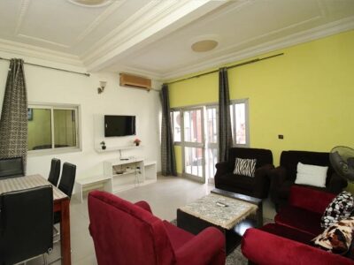 salon climatisé aménagé d'un espace TV_équipé de canapés-fauteuils-salle à manger-table basse et télévision_appartement meublé à douala-makepe